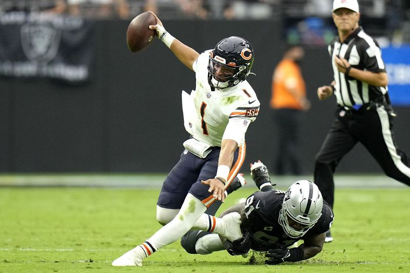 Bears quarterback Justin Fields berlari dengan bola menentang Raiders pada hari Ahad.