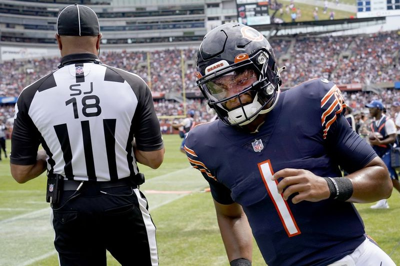 Le quart-arrière des Chicago Bears Justin Fields (1) revient sur le terrain derrière le juge de ligne Byron Boston après avoir décroché un premier essai au cours de la seconde moitié d