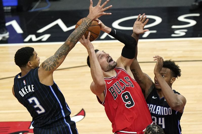 Center Bullsov Nikola Vucevic strelja, medtem ko napadalec Magica Chuma Okeke in center Wendell Carter Jr. branita v drugem polčasu v sredo zvečer.