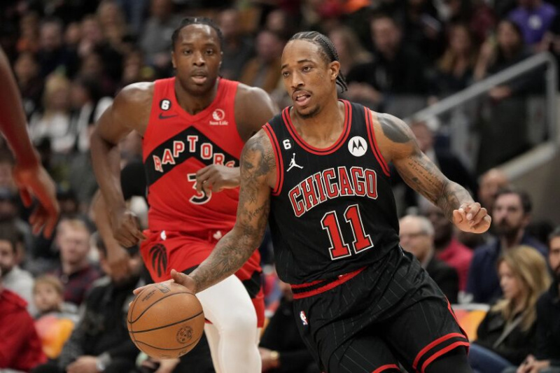   El alero de los Bulls, DeMar DeRozan, regatea mientras el alero de los Toronto Raptors, O.G. Anunoby persigue.
