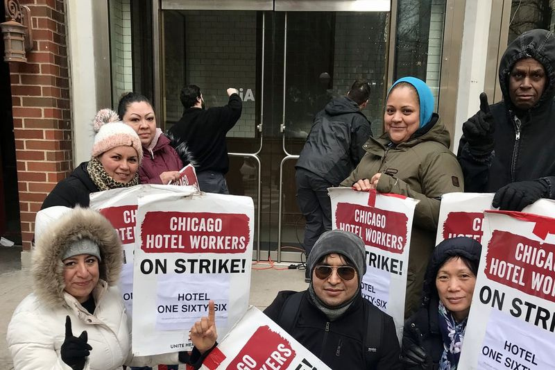 Streikuotojai, „Unite Here Local 1“ nariai, renkasi pirmadienį prie viešbučio adresu 166 E. Superior, kai darbuotojas nubraukia Cambria pavadinimą nuo durų.