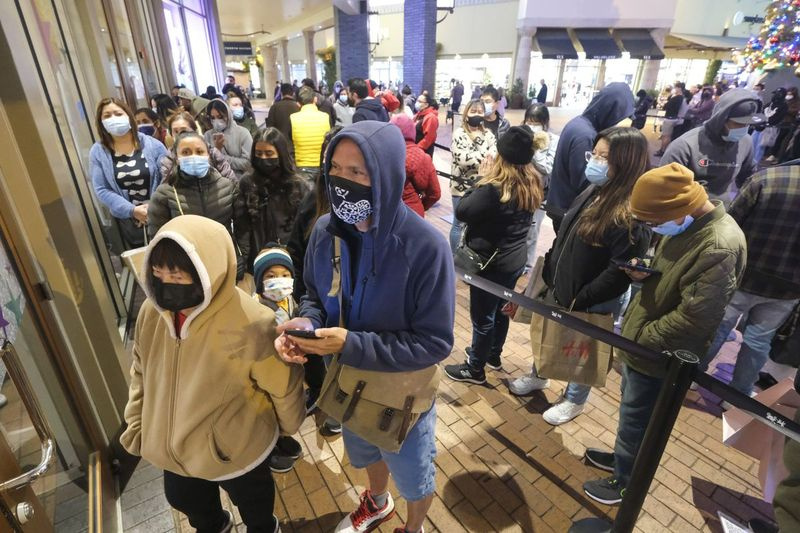 Les acheteurs du Black Friday, portant des masques faciaux, font la queue pour entrer dans un magasin des magasins Citadel Outlets à Commerce, Californie, le vendredi 26 novembre 2021. (AP Photo/Ringo H.W. Chiu)