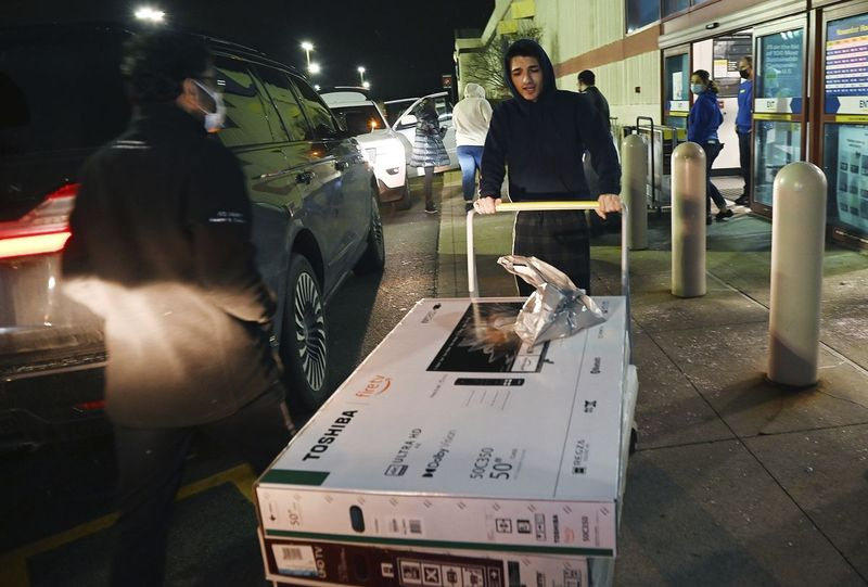 Sebastian Semma, 20 ans, de Novi, Michigan, transporte ses 50 nouveaux téléviseurs à écran plat dans son camion après les avoir achetés chez Best Buy le vendredi 26 novembre 2021.