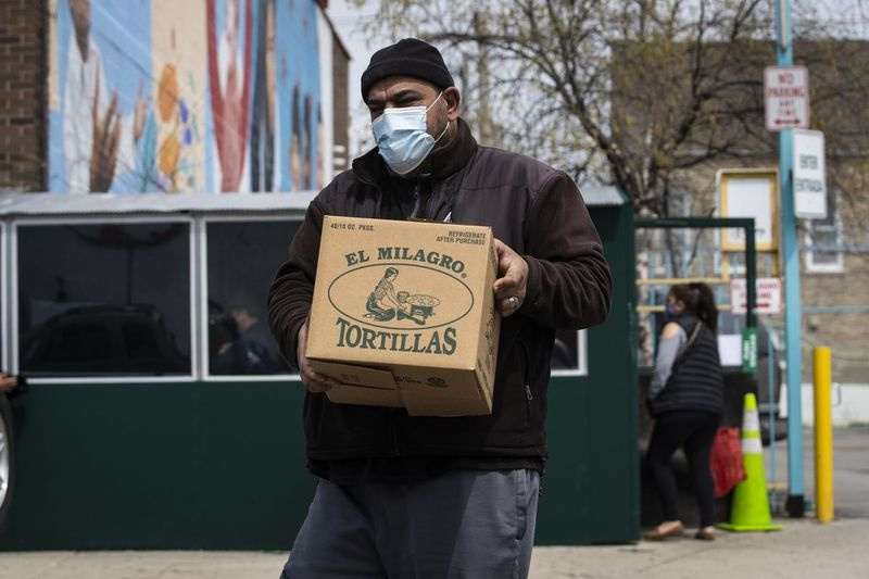En mand går ud fra Tortilleria El Milagro, 3048 W. 26th St. i Little Village, med en kasse med 40 pakker tortillas, det meste en person kunne købe på én gang, efter det var rygtet, at en af ​​virksomhedens fabrikker ville blive lukker i mindst to uger på grund af frygt for coronavirus-pandemien, mandag den 27. april 2020.