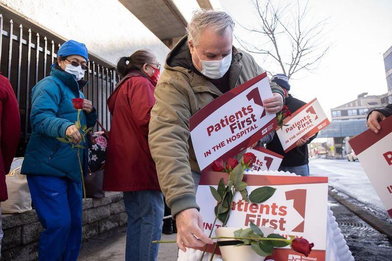 Las enfermeras del Community First Medical Center colocan rosas en un santuario temporal el 24 de febrero para tres trabajadores que murieron de COVID-19.