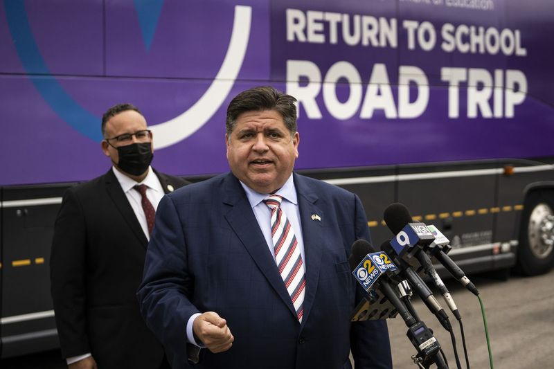 Ameriški minister za izobraževanje Miguel Cardona opazuje, kako se guverner J.B. Pritzker pogovarja z novinarji po ogledu Access Hawthorne Family Health Center v Ciceronu v torek.