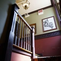 Un cartel viejo cuelga de la pared en la parte superior de las escaleras que conducen a un baño en Southport Lanes.