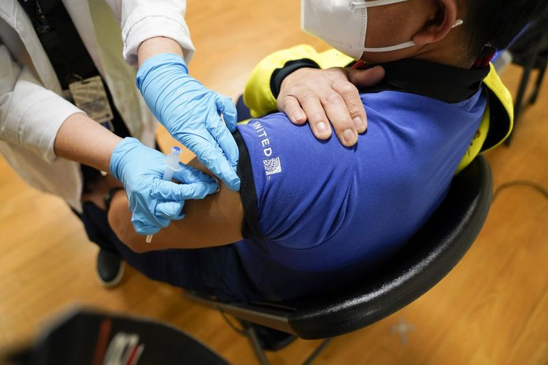 O persoană cu un tricou polo United Airlines este vaccinată împotriva coronavirusului.