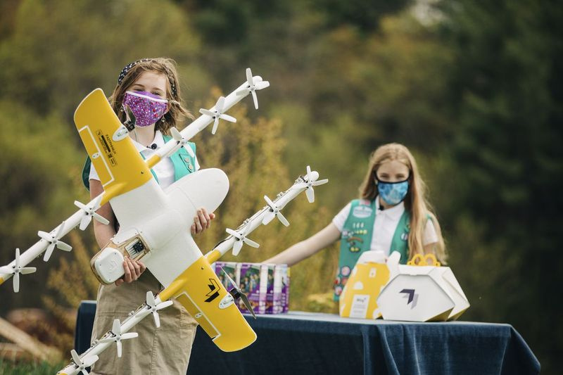 Jentespeidere Gracie Walker (til venstre) og Alice Goerlich med en Wing-leveringsdrone i Christiansburg, Virginia. Selskapet tester dronelevering av Girl Scout-kaker der.