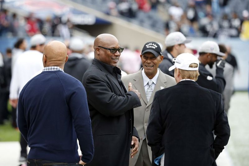Bývalí hráči NFL Bo Jackson, druhý zľava, a Willie Brown, tretí zľava, sa pred zápasom v Chicagu v roku 2015 rozprávajú s majiteľom Oakland Raiders Markom Davisom vpravo.