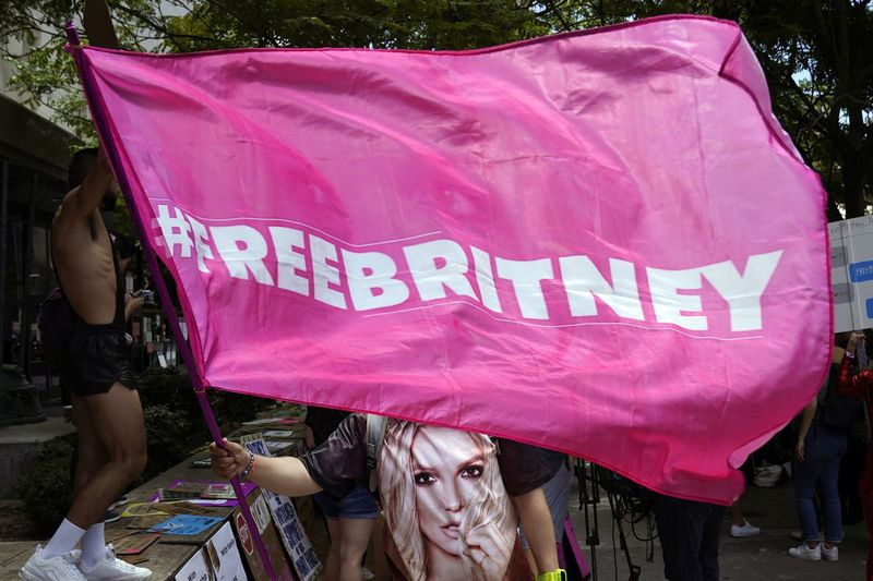 Ένας υποστηρικτής της Britney Spears κυματίζει μια σημαία Free Britney έξω από μια δικαστική ακρόαση σχετικά με τη συντηρητική υπηρεσία της ποπ τραγουδίστριας στο Δικαστήριο Stanley Mosk τον Ιούνιο, στο Λος Άντζελες.