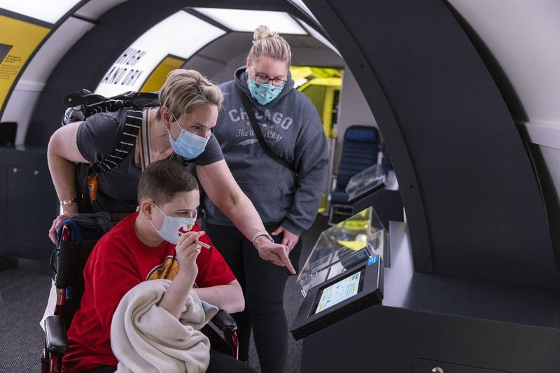 Eion Jiongco (od leve), Sandi Jiongco in Jennifer Cody se igrajo z enim od interaktivnih zaslonov na novo posodobljeni razstavi Boeing 727 v Muzeju znanosti in industrije v četrtek, 13. maja 2021.