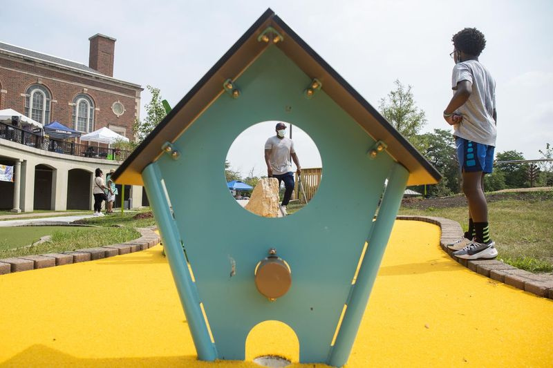 Khalid Hannah, a la izquierda, juega al minigolf con su hijo Khalil, a la derecha, el día de la inauguración del campo de minigolf Douglass 18 en el vecindario de North Lawndale el sábado por la mañana.