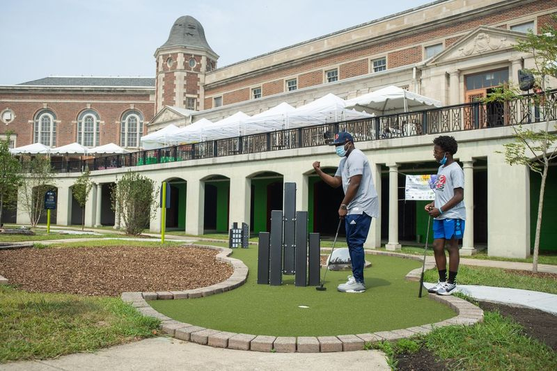 Khalid Hannah y su hijo Khalil juegan al minigolf el sábado en la inauguración del campo de minigolf Douglass 18 en el vecindario de North Lawndale.