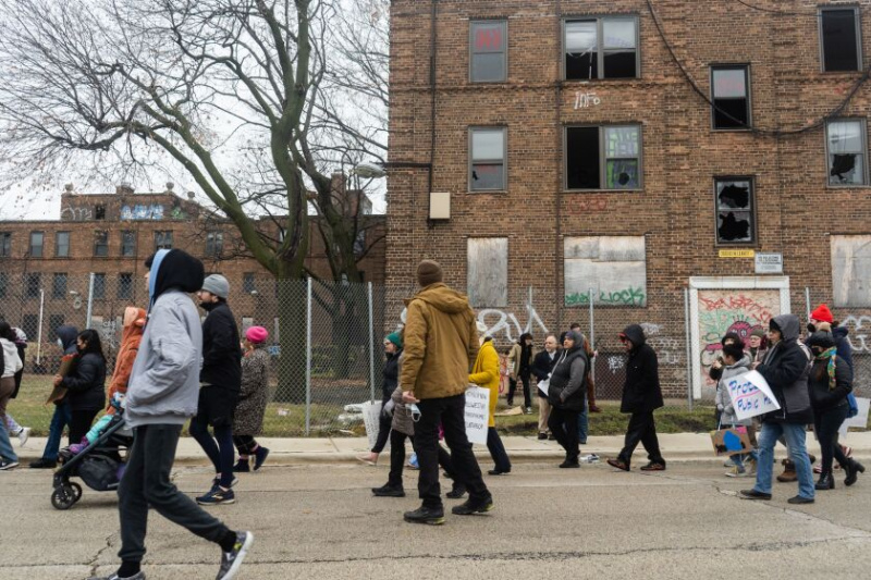   Protestniki hodijo pred vkrcanimi stavbami na ulici North Leavitt blizu soseske Lincoln Park med 10. letno procesijo »Las Posadas«, ki so jo organizirali Ekumenska zveza Logan Square, voditelji Lathrop in Palenque LSNA, da bi od župana Chicaga Lightfoota in Chicaga zahtevali Stanovanjska uprava je sanirala Lathrop Homes in jih dala na voljo temnopoltim in rjavim družinam z nizkimi dohodki, sobota zjutraj, 10. december 2022.