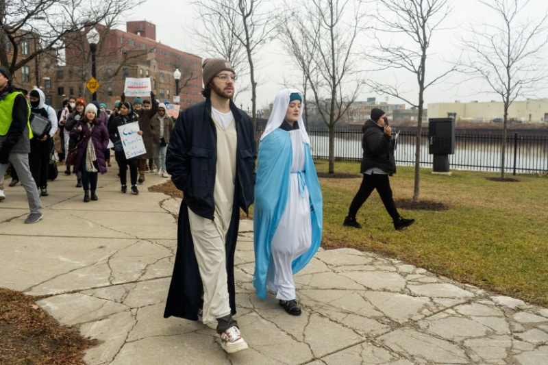   Orla Byrley, 15, ki je oblečena kot Mary, in Zach Davis, 29, ki je oblečen kot Joseph, hodita z protestniki po naravni poti Jimmyja Thomasa blizu Lathrop Homes na severni strani.