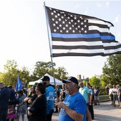 Ο Rich Kielbasa κρατά μια σημαία Thin Blue Line κατά τη διάρκεια μιας τελετής μνήμης και προσευχής για την πεσμένη αξιωματικό Ella French έξω από το αστυνομικό τμήμα της 22ης Περιφέρειας την Τετάρτη.