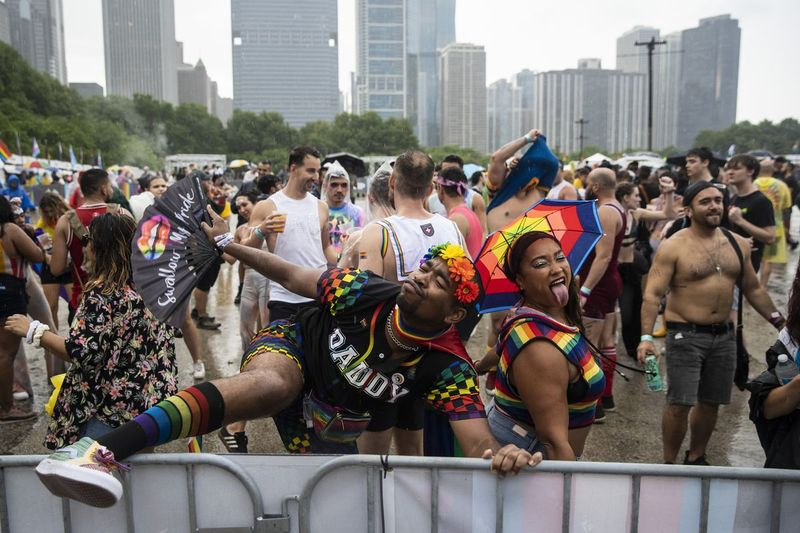 Pengunjung festival menari dalam hujan petang Sabtu semasa Pride in the Park di Grant Park.