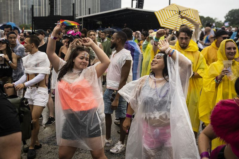 Pengunjung festival menari dalam hujan petang Sabtu semasa Pride in the Park di Grant Park.