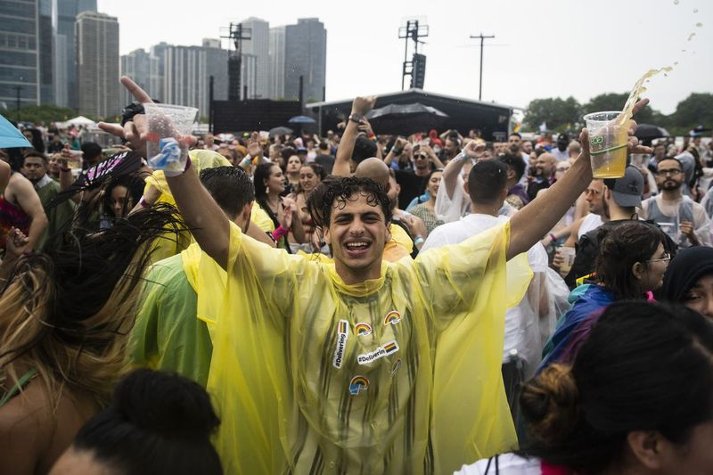 Pengunjung festival menari dalam hujan petang Sabtu semasa Pride in the Park di Grant Park.