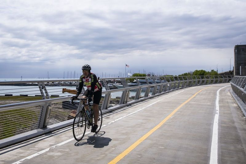 Pirmdienas rītā, 2020. gada 10. maijā, velosipēdists brauc uz Navy Pier Flyover netālu no nesen pabeigtās takas daļas, kas ved uz Lake Shore Drive tiltu pāri Čikāgas upes grīvai.