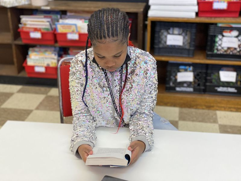 Kinadee Jordan, 13 ans, lit un de ses livres dans la bibliothèque de l