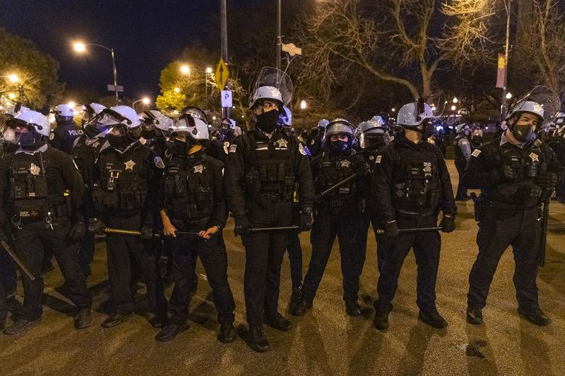 Chicago-polisen bildar en linje med batonger ut efter en tidigare sammandrabbning med demonstranter nära Logan Square Park i Chicago fredagen den 16 april 2021, en dag efter släppet av video som visar en Chicago-polis dödligt skjuta en 13-åring förra månaden .
