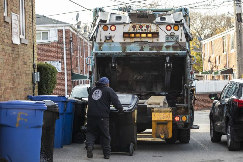Ein Arbeiter des städtischen Straßen- und Sanitärministeriums belädt einen Müllwagen im Block 7500 des North Ridge Boulevard im Rogers Park