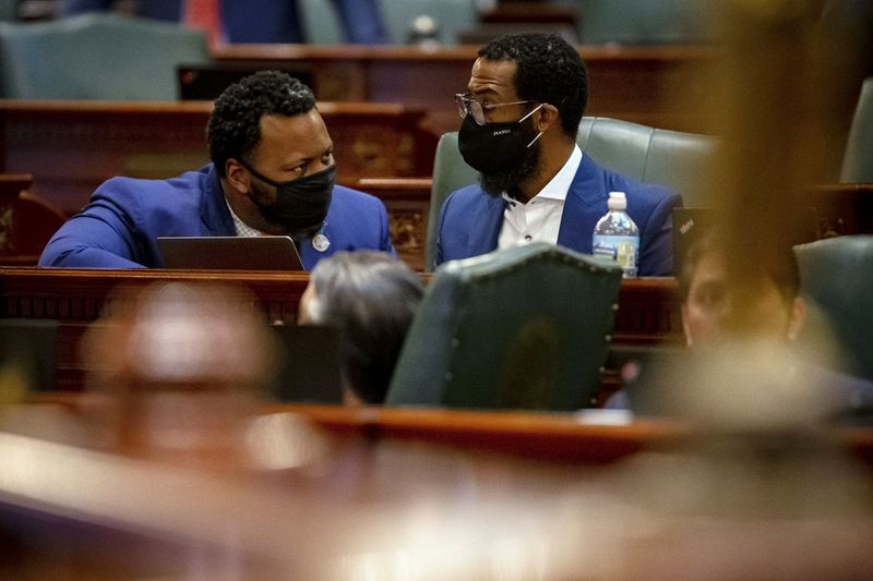 O deputado estadual Kam Buckner, D-Chicago, à esquerda, conversa com o deputado estadual Curtis Tarver, D-Chicago, no plenário da Câmara dos Representantes de Illinois no último dia da sessão de primavera.