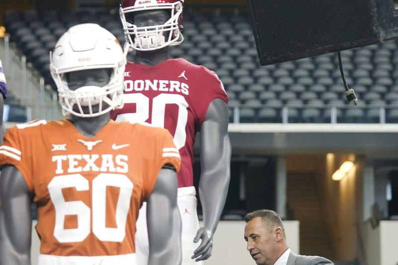 Trenér texaského fotbalu Steve Sarkisian prochází během velkých 12 mediálních dnů kolem figurín v uniformách Texasu a Oklahomy.