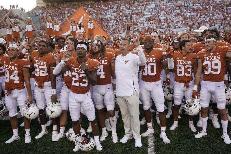 O técnico de futebol do Texas, Steve Sarkisian, do centro, junta-se aos jogadores para cantar The Eyes of Texas após o jogo de sábado contra Louisiana-Lafayette.