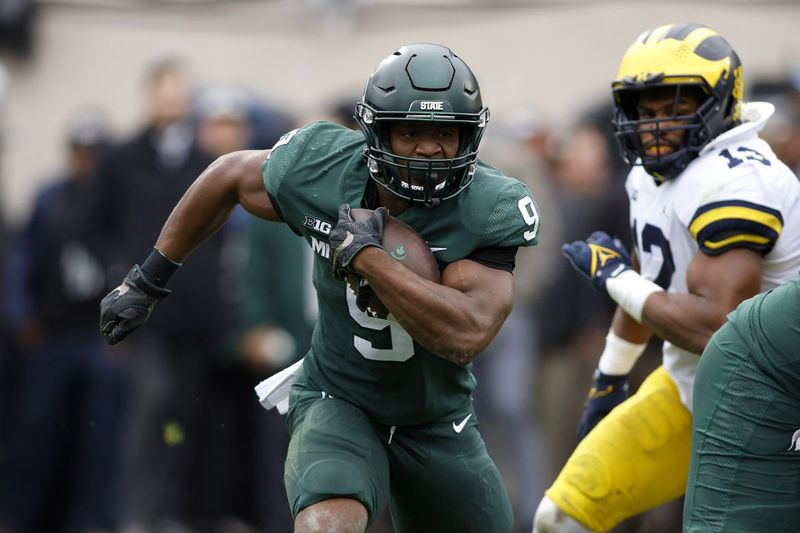 Kenneth Walker III (9) du Michigan State se précipite contre Josh Ross du Michigan au cours du premier quart du match de samedi. L