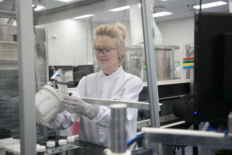 Un asociado de procesamiento de muestras agrega una etiqueta de identificación a un frasco de muestras en Exact Sciences Laboratories en Madison. Hacer un seguimiento de la información del paciente es clave para el proceso.