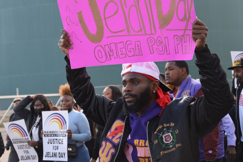 Član Omega Psi Phi Fraternity, Inc. nosi znak v podporo svojemu bratu iz bratovščine Jelani Dayu na shodu v Peruju, Illinois, ta teden.