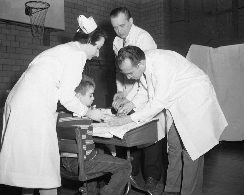 Le Dr Jonas Salk, scientifique de Pittsburgh qui a découvert le vaccin contre la polio, administre une injection à un garçon non identifié à l