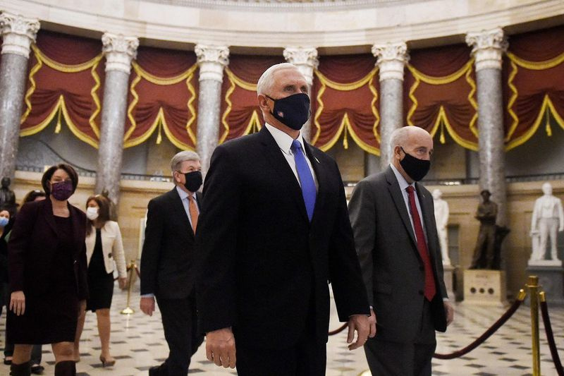 Pada 7 Januari, Naib Presiden Mike Pence (C) berjalan pulang dari Dewan Dewan diikuti perarakan Senat yang membawa kotak undi pilihan raya di Capitol.