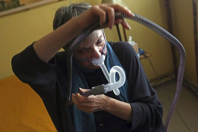 Pacientka so spánkovým apnoe ukazuje, ako si nasadzuje masku CPAP – masku, na ktorú sa rozhodla po vyskúšaní 26, ktorá jej nevyhovovala alebo jej nevyhovovala.