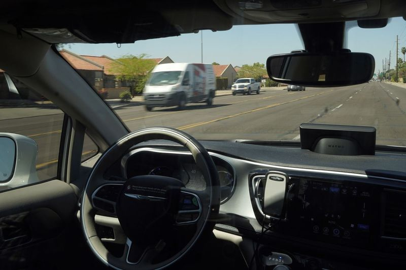 En Waymo-minivan rör sig längs en stadsgata som en tom förarsäte och en rörlig rattdriven passagerare under en åktur med autonoma fordon i Chandler, Ariz. Den amerikanska regeringens motorvägssäkerhetsbyrå vill undersöka mönster som involverar krockar av helt autonoma fordon eller delvis automatiserade förare hjälpsystem.
