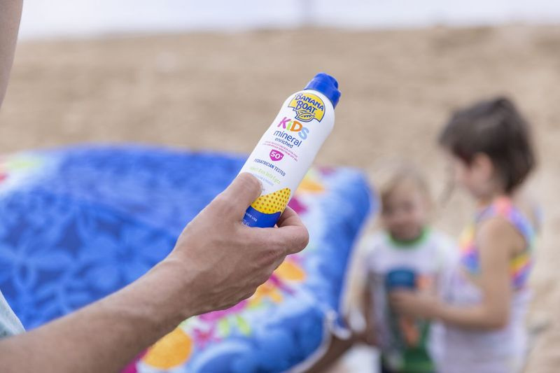 Ian Merrill überprüft während eines Tagesausflugs in Foster Beach die Inhaltsstoffe der Sonnencreme-Flasche der Familie. Er und seine Frau Michelle sagen, dass sie versuchen, Parabene und Oxybenzon zu vermeiden.