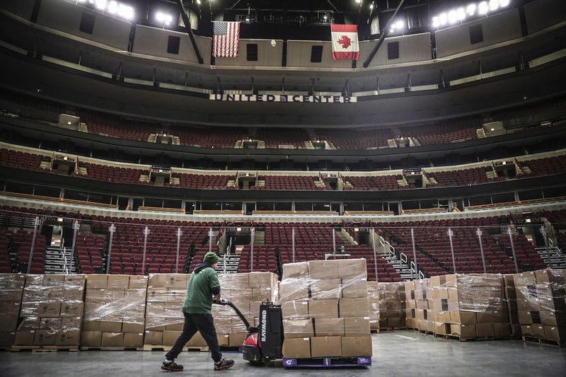 Ein Arbeiter bewegt eine Kiste mit gespendeten Lebensmitteln auf den Boden des United Center in Chicago. Viele Familien werden ihre staatlichen Anreizzahlungen für Nahrung, Medikamente oder Wohnen benötigen.
