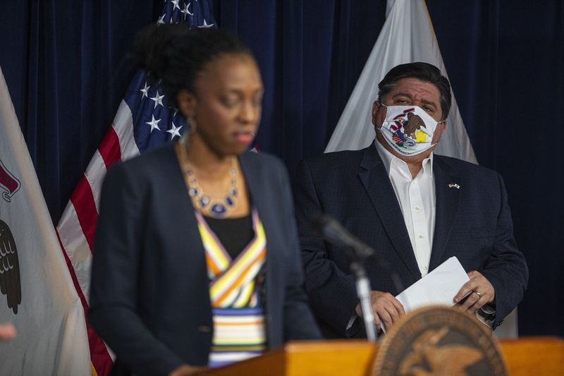 Guvernér J.B. Pritzker poslouchá, jak minulý týden hovořil ředitel Illinoisského ministerstva veřejného zdraví Dr. Ngozi Ezike během každodenní aktualizace COVID-19.