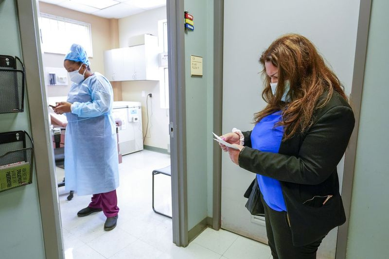 Angelita Ramo, geht ihren Impfausweis durch, während sie darauf wartet, dass die lizenzierte praktische Krankenschwester Karja Austin sie mit der zweiten Dosis des Moderna-COVID-19-Impfstoffs im Joseph P. Addabbo Family Health Center im Stadtteil Far Rockaway im Stadtteil Queens von New impft York.