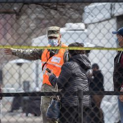 En medlem av Illinois National Guard dirigerar människor utanför massvaccinationsplatsen för covid-19 som sattes upp på parkeringsplatsen vid United Center i Near West Side-området på öppningsdagen för den nya massvaccinationsplatsen, tisdag morgon, mars 9, 2021
