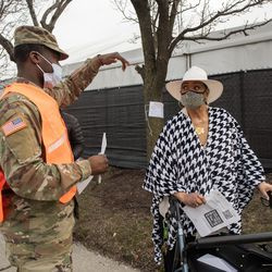 Marjorie Simmons pratar med en medlem av Illinois National Guard medan hon väntar i kö utanför massvaccinationsplatsen för COVID-19 som sattes upp på parkeringsplatsen vid United Center.