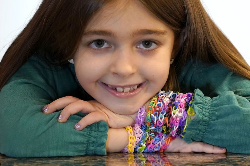 Hayley Orlinsky posiert am Mittwoch, den 2. Dezember 2020, für ein Porträt mit mehreren bunten Gummiband-Armbändern, die sie in ihrem Haus in Chicago herstellt.