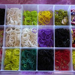 Bunte Gummibänder sitzen in einem Plastikbehälter, der darauf wartet, dass die 7-jährige Hayley Orlinsky sie zu Armbändern verarbeitet.