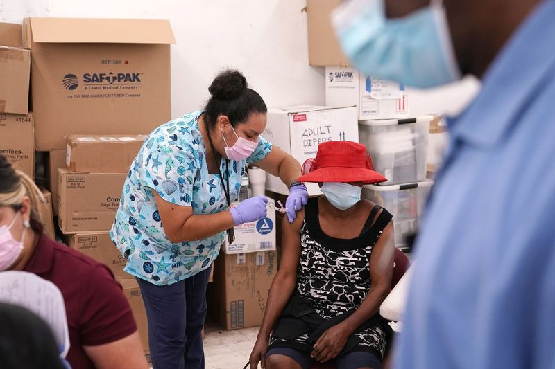 På dette arkivfoto den 10. april 2021 administrerer registreret sygeplejerske Ashleigh Velasco, til venstre, Johnson & Johnson COVID-19-vaccinen til Rosemene Lordeus, til højre, på en klinik, som holdes af Healthcare Network i Immokalee, Fla.