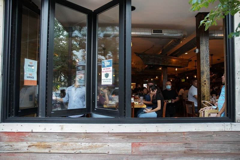 La Costa Mariscos-manager Alejandro schuift in september de ramen aan de voorkant van het Cragin-restaurant open, voor een tweede COVID-19-stop in november. Restaurants mogen heropenen in zes van de 11 regio