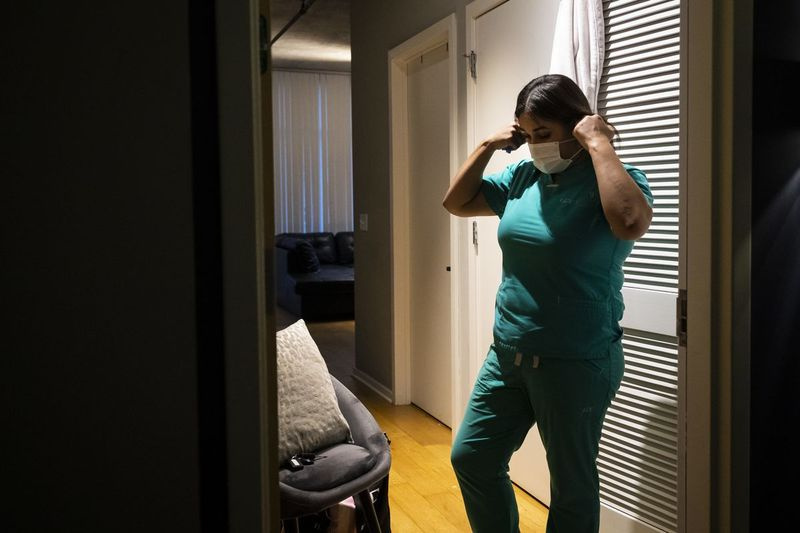 Slaugytoja praktikuojanti slaugytoja Capri Reese nusiima veido kaukę, dezinfekuoja batus ir įdeda šveitiklius į skalbimo mašiną, prieš iš karto nusiprausdama po dušu South Loop bute po 12 valandų pamainos Roseland bendruomenės ligoninėje, kur mirė trys nuo COVID-19 sergantys pacientai, antradienį. 2020 m. balandžio 28 d., popietė.