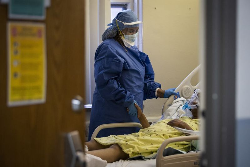 Slaugytoja Jeanette Averett guodžia 56 metų moterį, sergančią COVID-19, kuri kovojo su nerimu dėl savo neinvazinio ventiliatoriaus Rozlando bendruomenės ligoninėje Tolimųjų Pietų pusėje balandžio mėn.